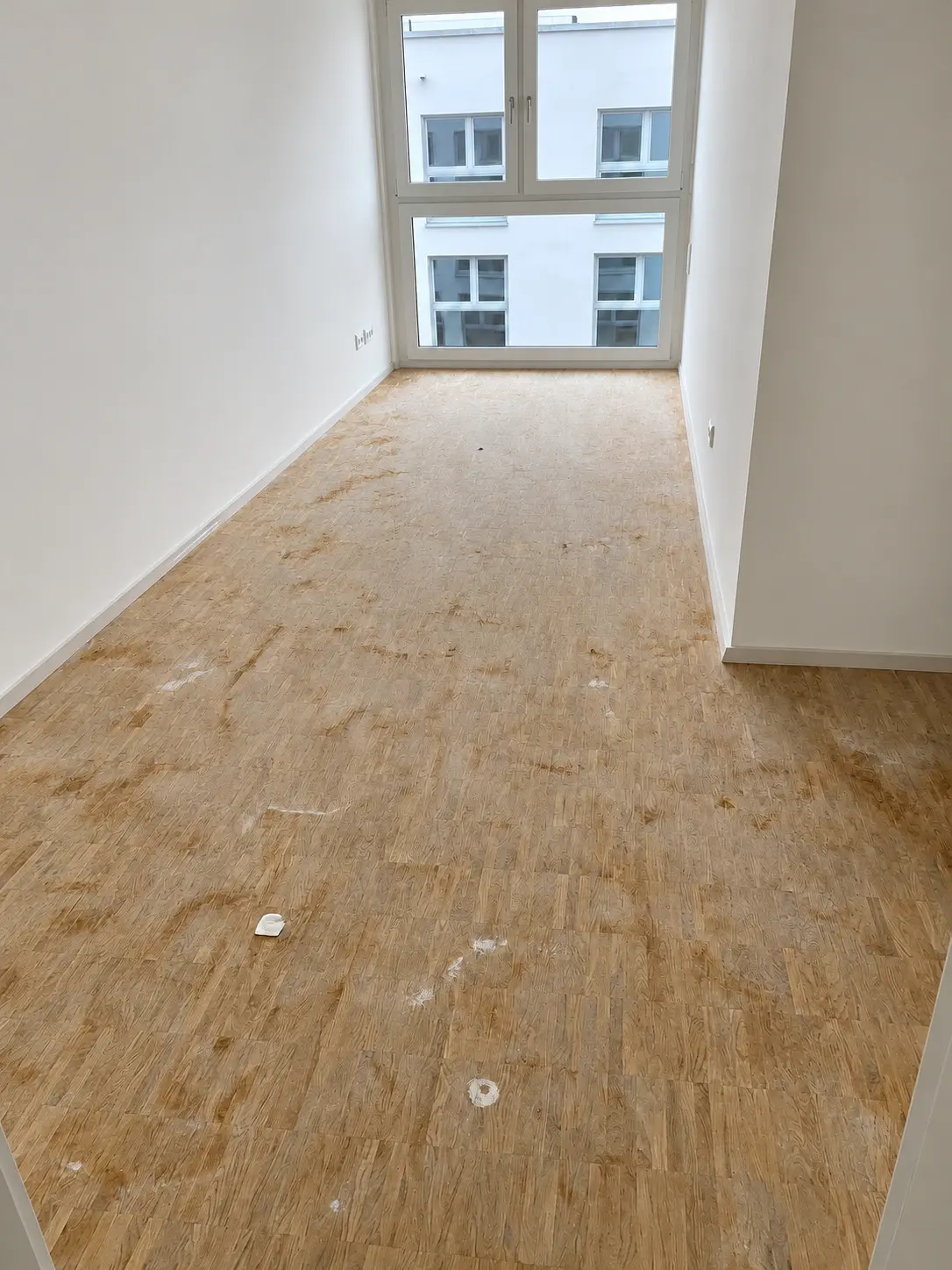 Raum mit Holzboden und sichtbaren Rückständen vor der Reinigung